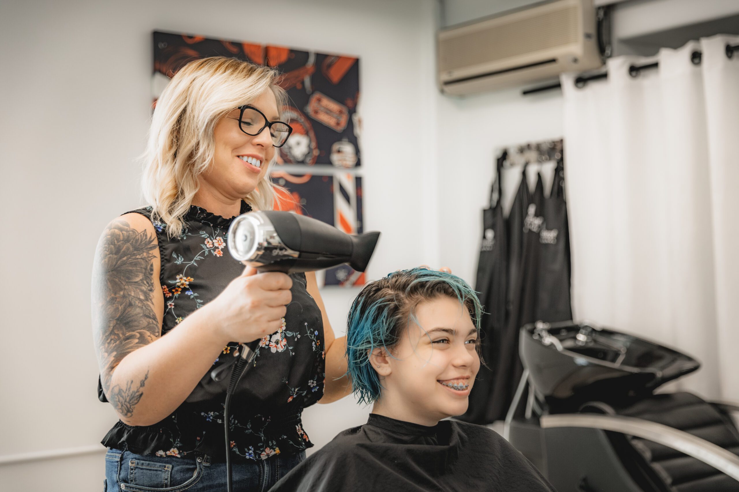 Hairstylist blow drying client's hair